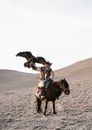 Man in White Shirt Riding Brown Horse on Brown Sand