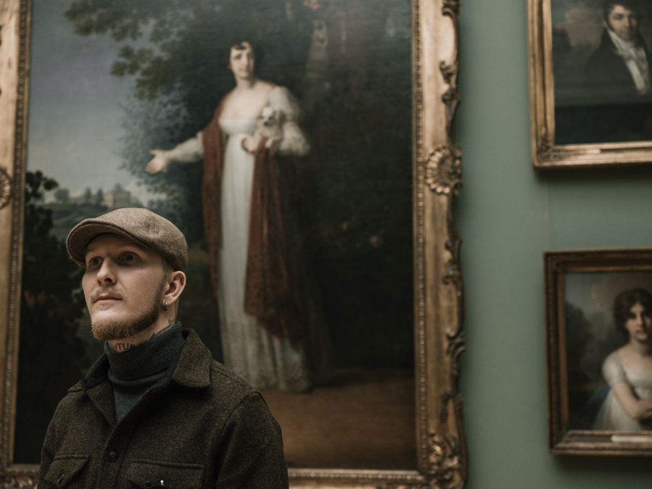 a man stands in an art gallery admiring classical paintings on display