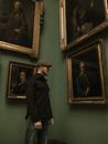Man Staring at Portraits in Museum