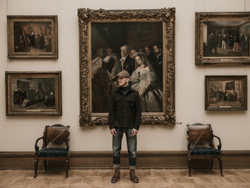 Man Standing in front of Paintings in a Museum