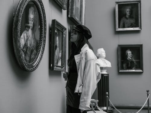Woman Looking at Paintings and Sculptures in Museum