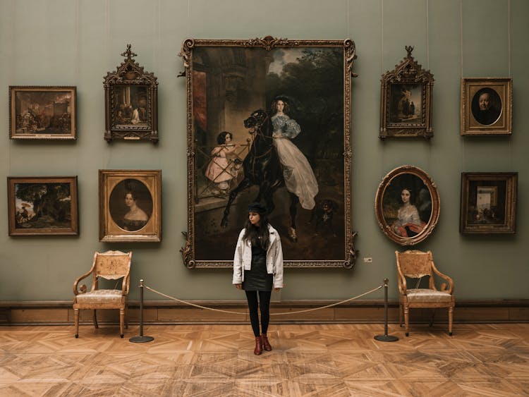 Woman Standing In Front Of Paintings In A Museum