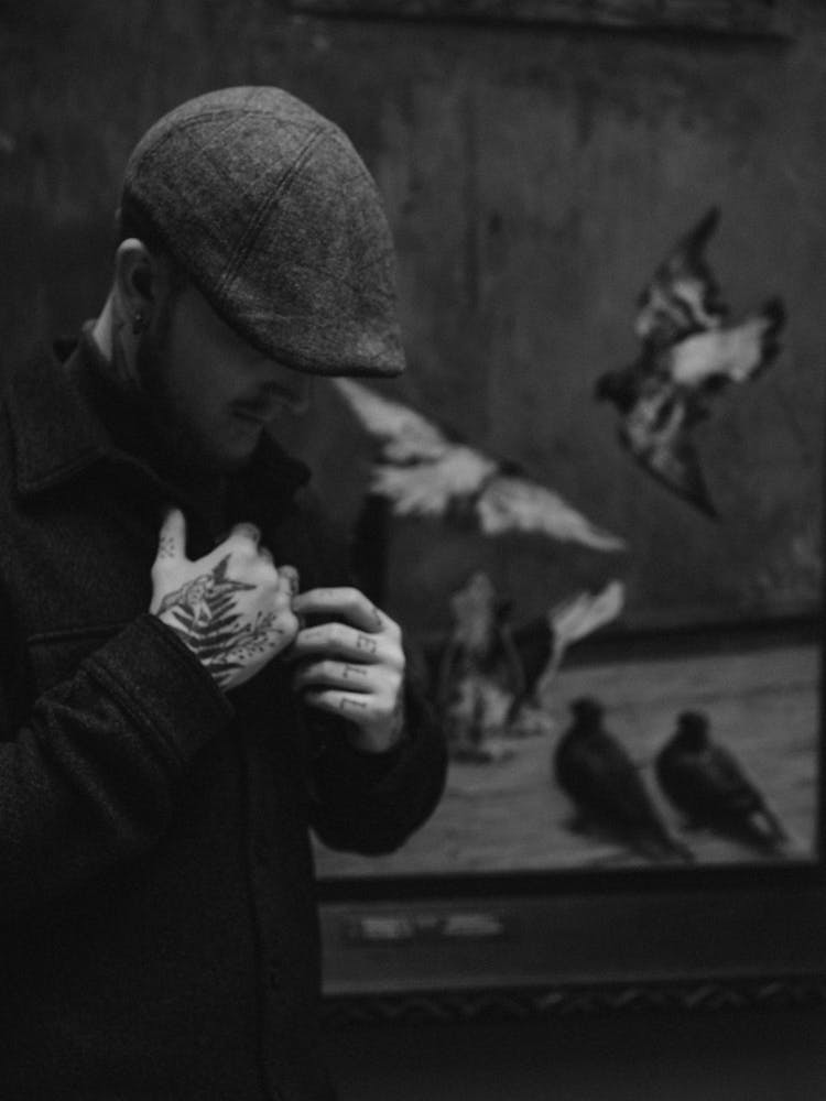 Black And White Photo Of Tattooed Man Touching His Chest