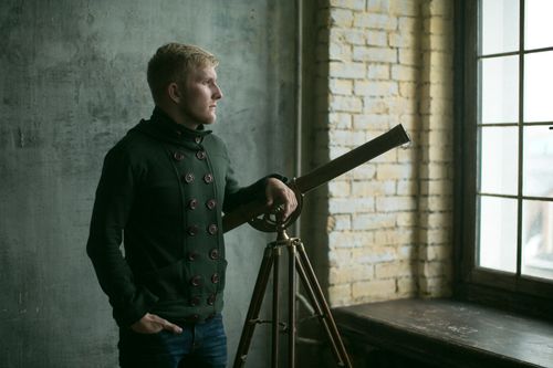 Free A thoughtful man standing by a telescope in an industrial loft. Perfect for themes of exploration. Stock Photo