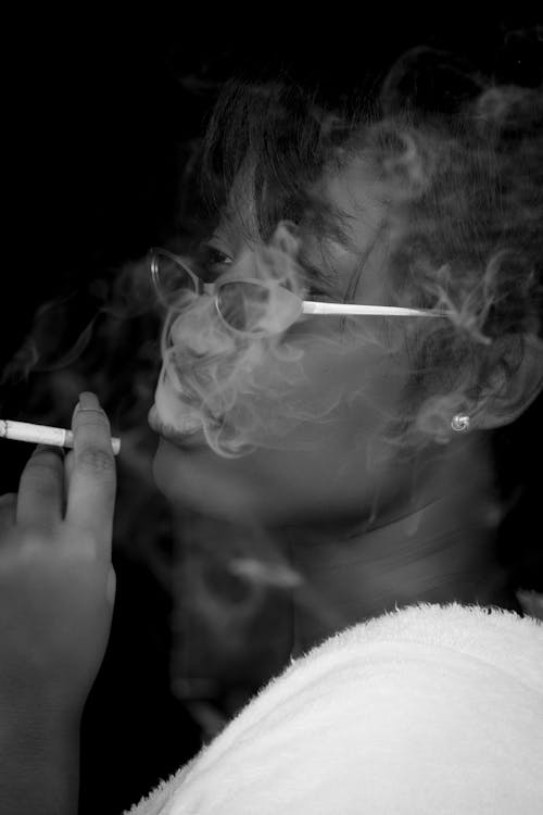 Grayscale Photo of Woman Smoking Cigarette