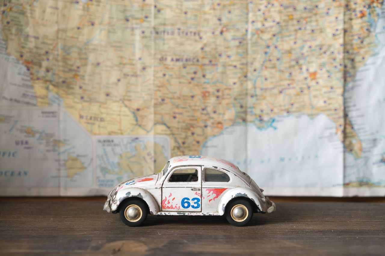 close up of a vintage toy car model with map background symbolizing tr