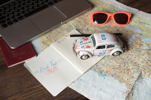 Flat lay of a road trip plan featuring maps, passport, toy car, and travel essentials.