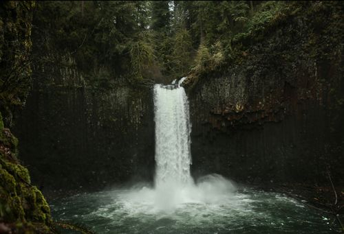 Free A breathtaking waterfall cascades into a serene pool in a lush forest setting. Stock Photo