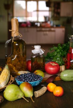 A variety of fresh fruits, vegetables, and olive oil bottles arranged in a kitchen setting for cooking inspiration.