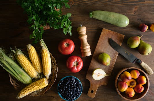 Top view of fresh fruits and vegetables including corn, pears, and tomatoes on a kitchen counter.