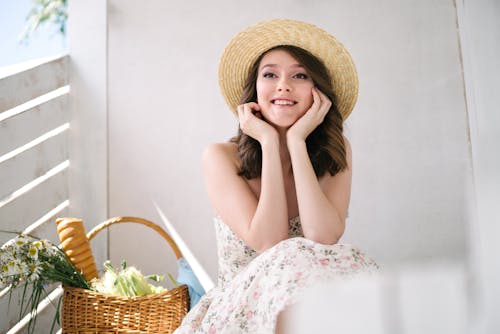 Pretty Girl in Summer Dress and Straw Hat Sitting on Porch