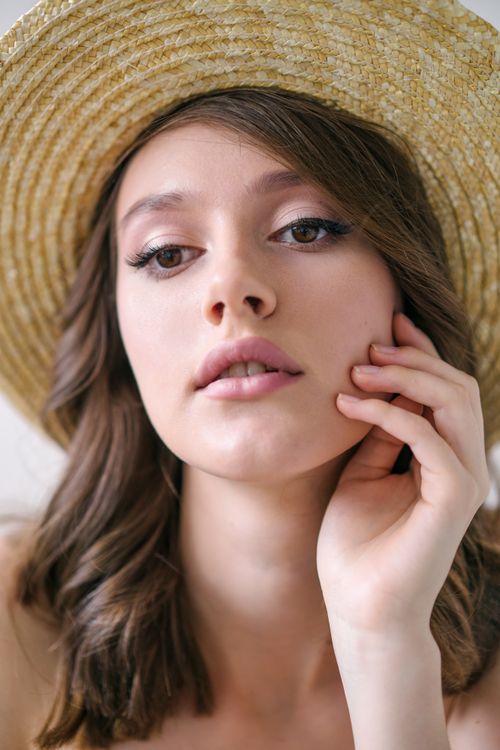 Free Close-up portrait of a woman wearing a straw hat, exuding summertime elegance and beauty. Stock Photo
