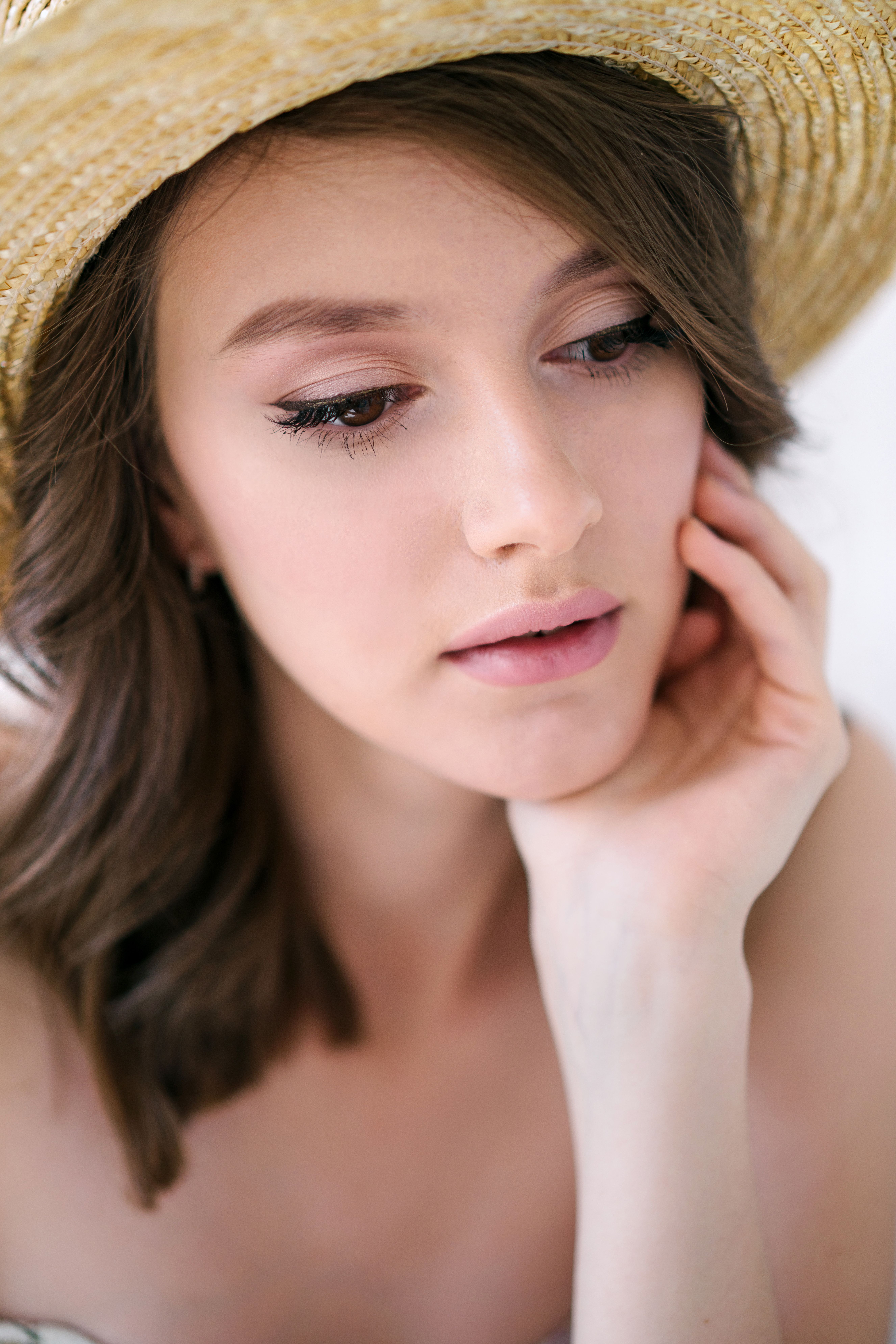 Close-up portrait of a woman wearing a straw hat, showcasing elegance and summer vibes.