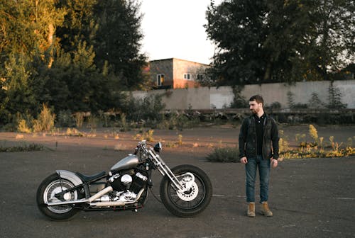 Free Man Standing next to and Looking at a Motorcycle Stock Photo