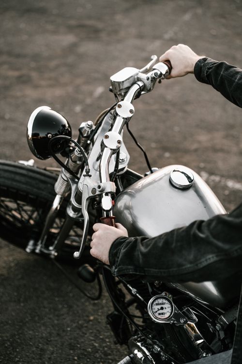 Free Detailed view of male hands on a vintage motorcycle handlebar outdoors. Stock Photo