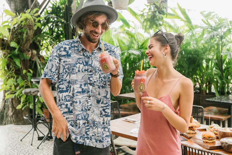 Amused Couple Drinking Cooling Fruit Smoothie in Cafeteria Patio