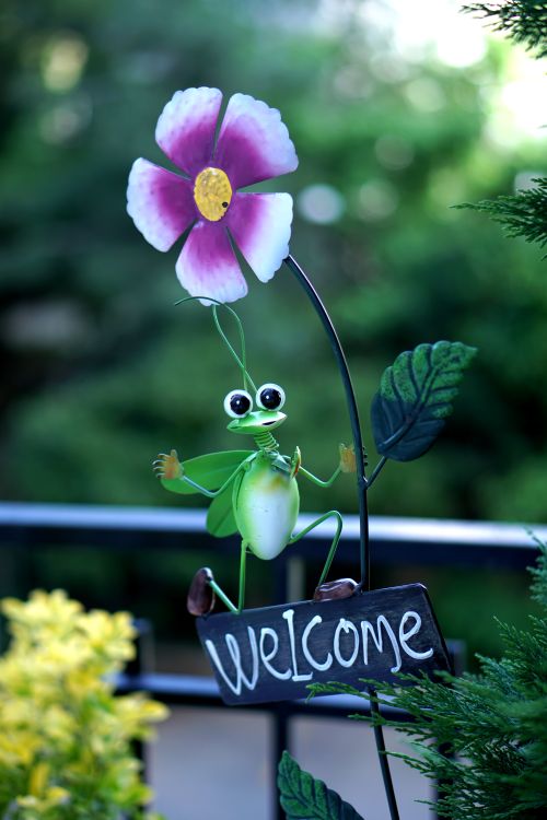 Free Colorful garden figurine with flower and 'Welcome' sign, adding charm to outdoor decor. Stock Photo