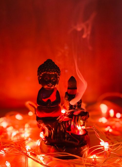 Free A serene Buddha figurine surrounded by warm, glowing lights creating a tranquil atmosphere. Stock Photo