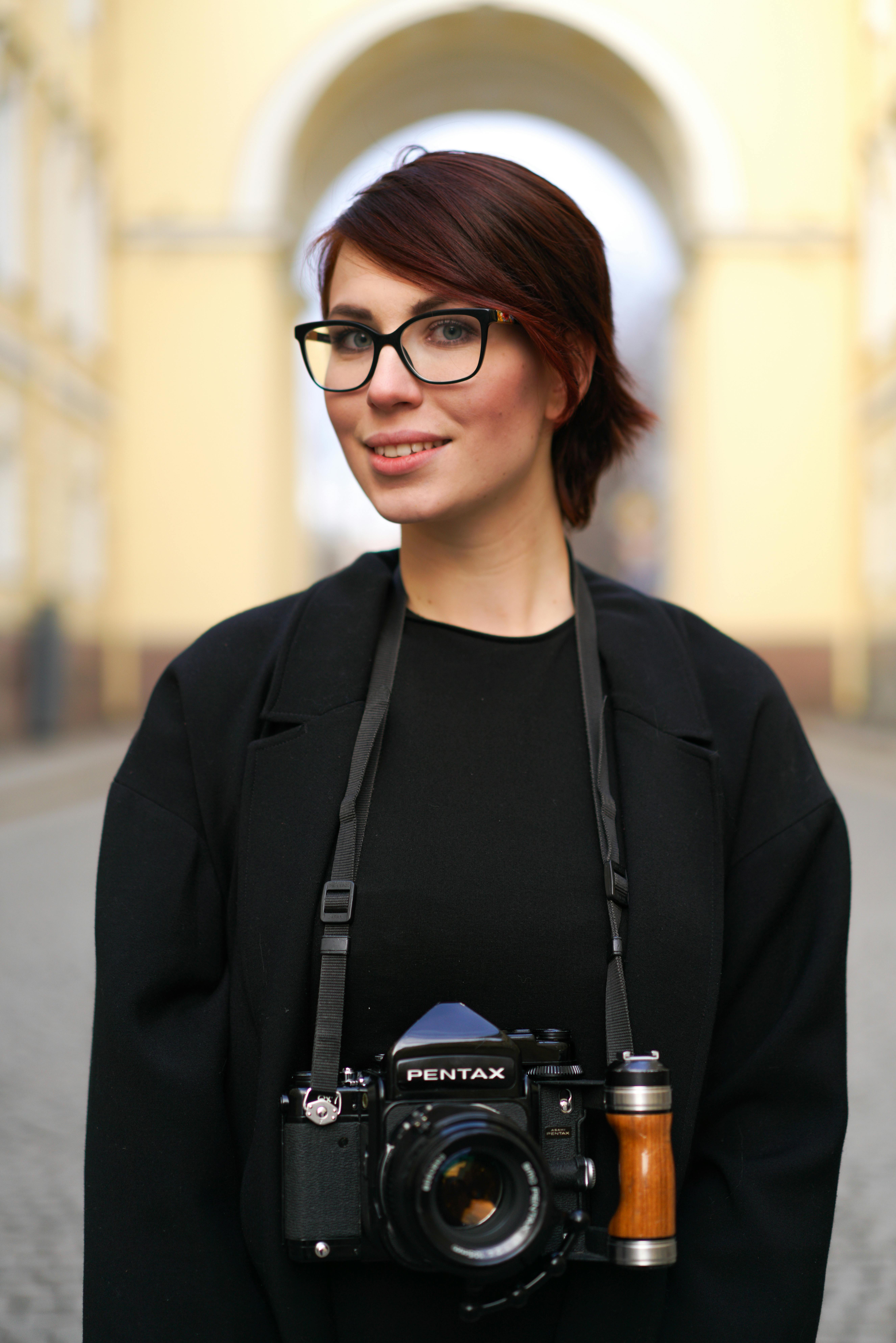 Professional female photographer smiling with camera on city street.