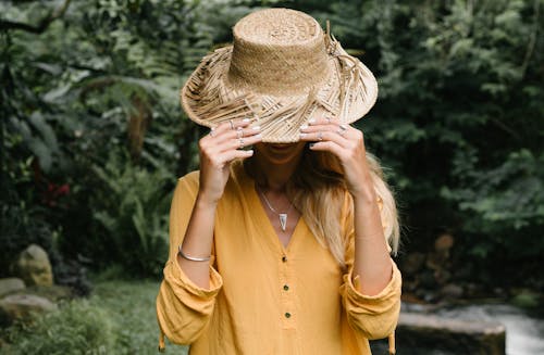 Free Woman in Yellow Button Up Long Sleeve Shirt Face Covered with Straw Hat Stock Photo