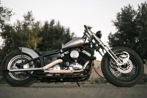 Free Side view of a classic vintage motorcycle parked outdoors on the road. Stock Photo