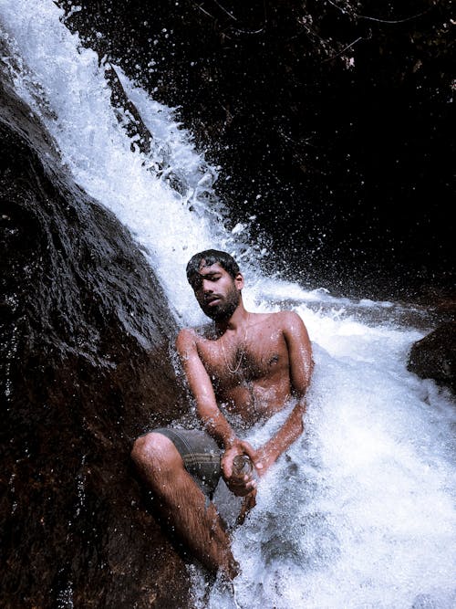 Shirtless Man Relaxing on Stream Water in a Waterfalls