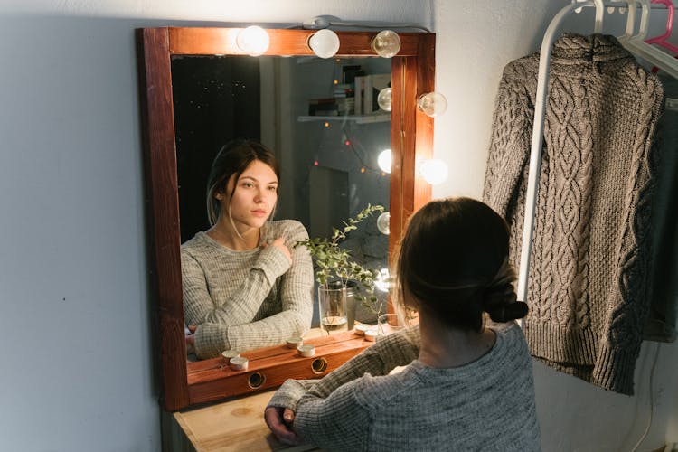 Woman In Gray Sweater Staring In Front Of A Mirror