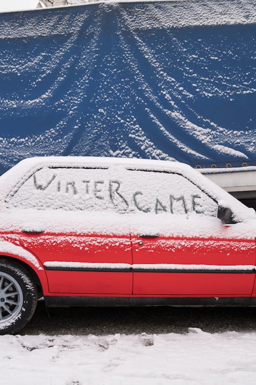 Snow Covered Red Car Parked on Road