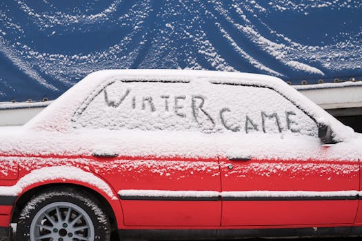 Snow-covered car with 'WINTER CAME' written on the window, showcasing a winter scene.