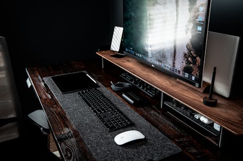 High angle of contemporary workplace with modern devices including desktop with keyboard and netbook smartphone and computer mouse with tablet