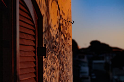 Close-up of abstract wall art and shutters during a vibrant sunset, creating an urban atmosphere.
