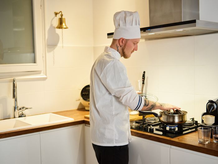 Chef in whites working a pan at the stove — photo by ArtHouse Studio on Pexels