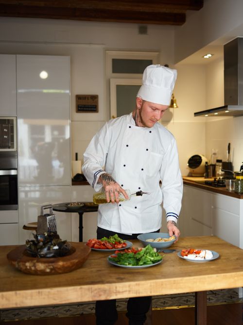Free Professional chef in white uniform preparing ingredients for a healthy meal in a modern kitchen setting. Stock Photo