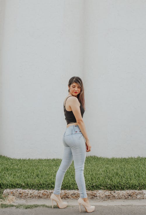 Free Full body side view of slim young female showing booty while standing on asphalt path Stock Photo