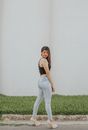Full body side view of slim young female showing booty while standing on asphalt path