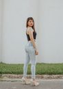 Side view full body of attractive young female with red lips wearing jeans and heels standing on paved street