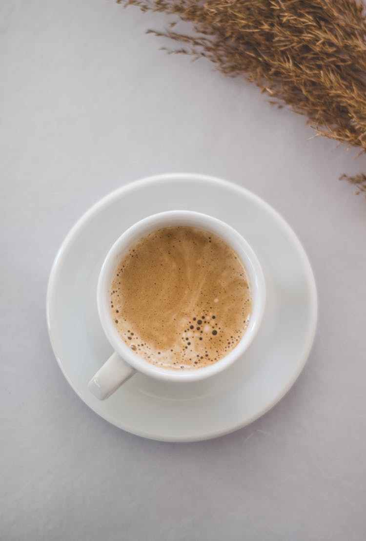 Cup Of Foamy Coffee On White Table