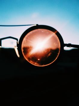 A striking lens flare captured through glass with a warm sunset background.