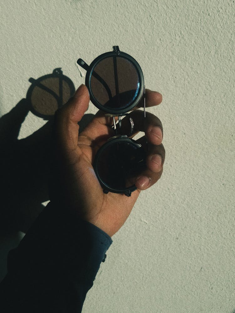 Person Holding Black Round Sunglasses 