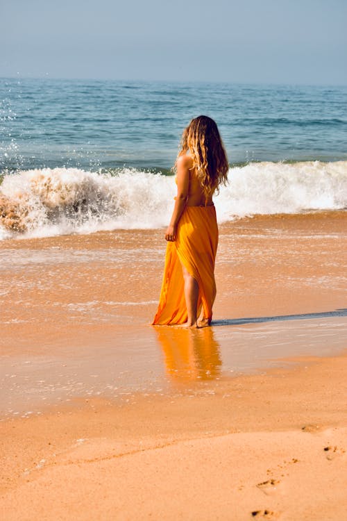 Free Woman in Yellow Bikini Cover Up Skirt Standing on Beach Stock Photo
