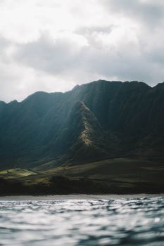 Scenic view of mountains under a dramatic cloudy sky with rippling water in foreground.