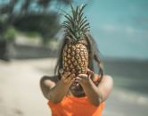 Person in Orange T-shirt Holding Pineapple Fruit