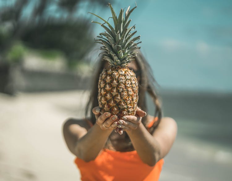 Woman Hiding Face Behind Pineapple 