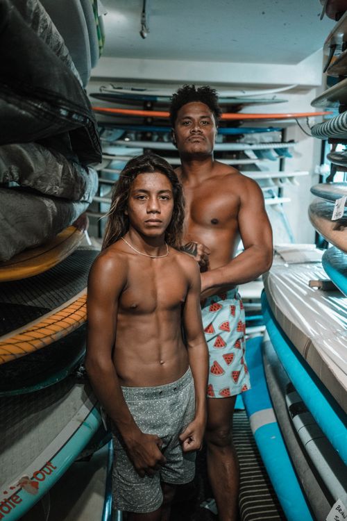 Free Two athletes pose in a surfboard storage room. Stock Photo