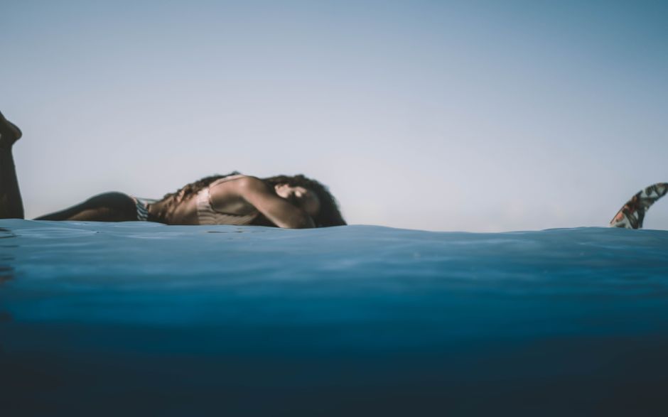 A woman enjoying a peaceful moment by the water, evoking summer vibes and tranquility.