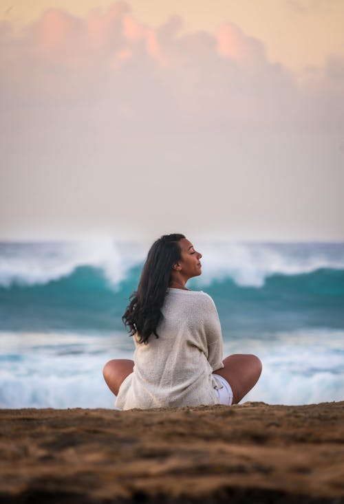 Free Woman Sitting with Legs Crossed on a Beach Stock Photo