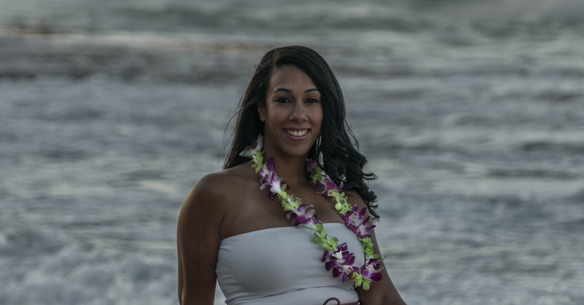 Photo by ArtHouse Studio A woman in a floral lei enjoys the ocean view while sitting on rocks.
