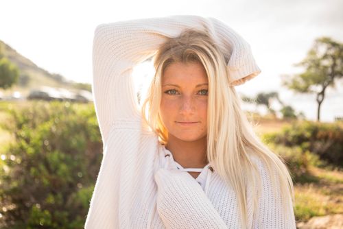 Woman with long blonde hair in a white knit top