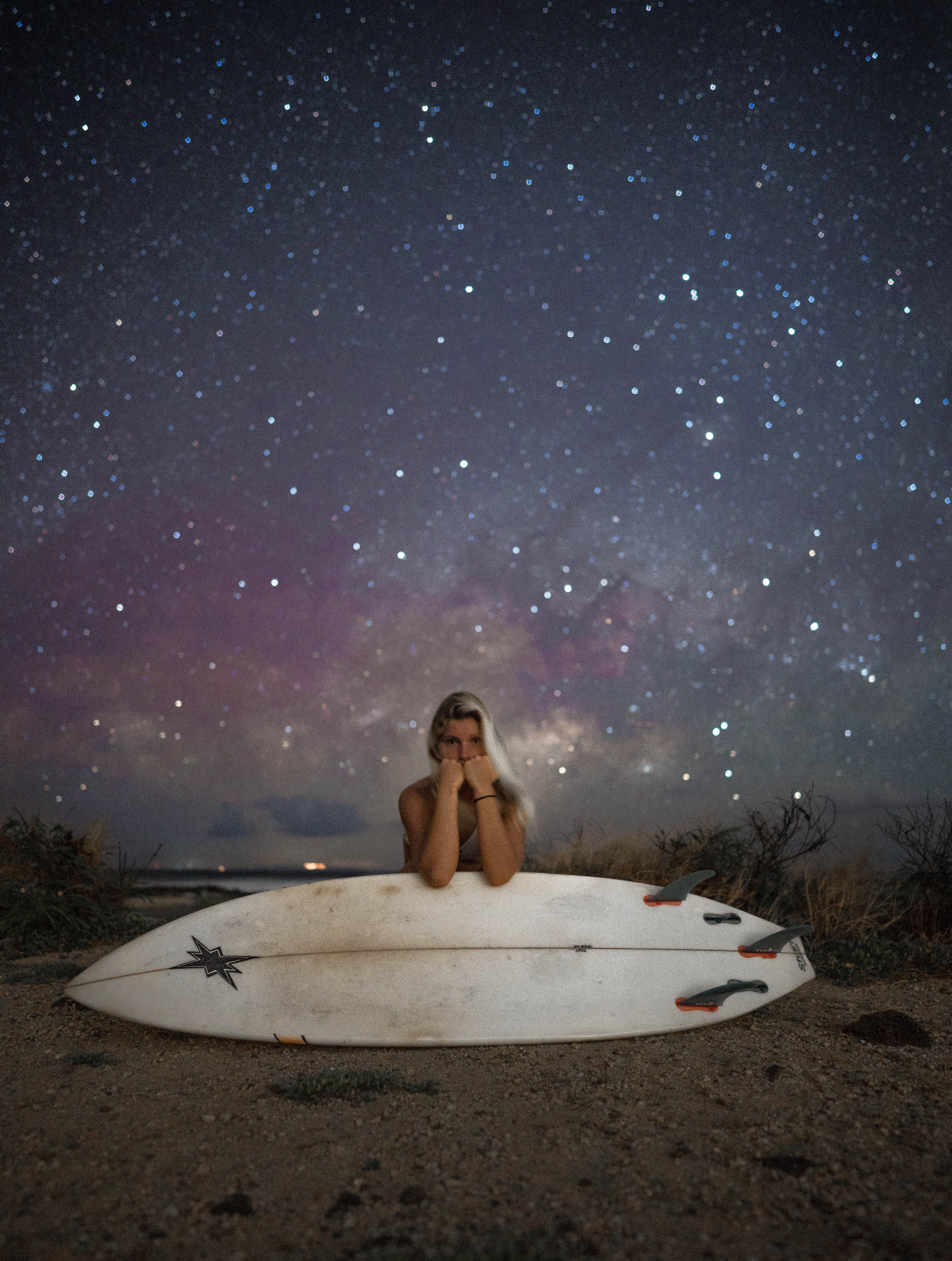 一位拿着冲浪板的女人站在令人惊叹的星空下