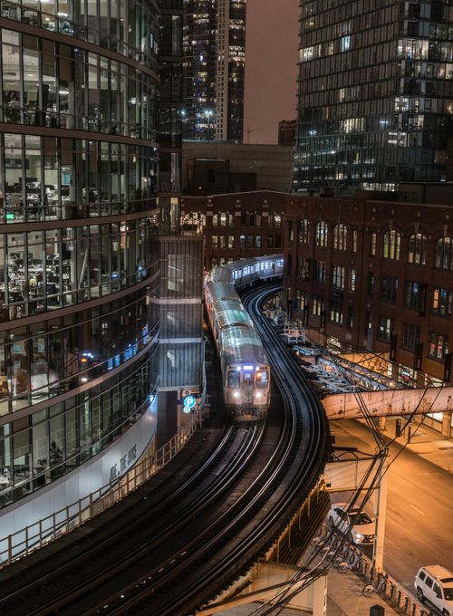 Free Urban train navigating through illuminated city buildings at night. Stock Photo